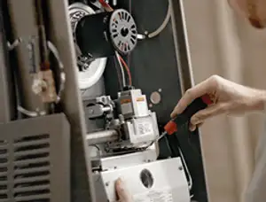 Furnace repair technician inspecting internal components and wiring in Flagstaff, AZ