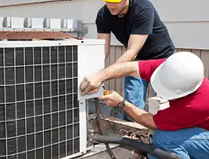 HVAC technicians repairing an outdoor AC unit on a rooftop in Flagstaff, AZ