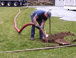 Septic pumping technician servicing a residential septic tank with a vacuum hose in Flagstaff, AZ