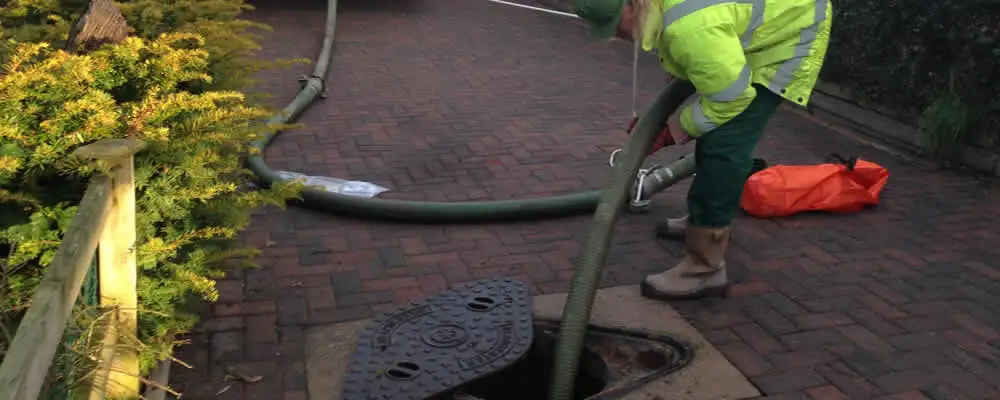 Septic tank cleaning technician servicing a septic tank with a vacuum hose in Flagstaff, AZ